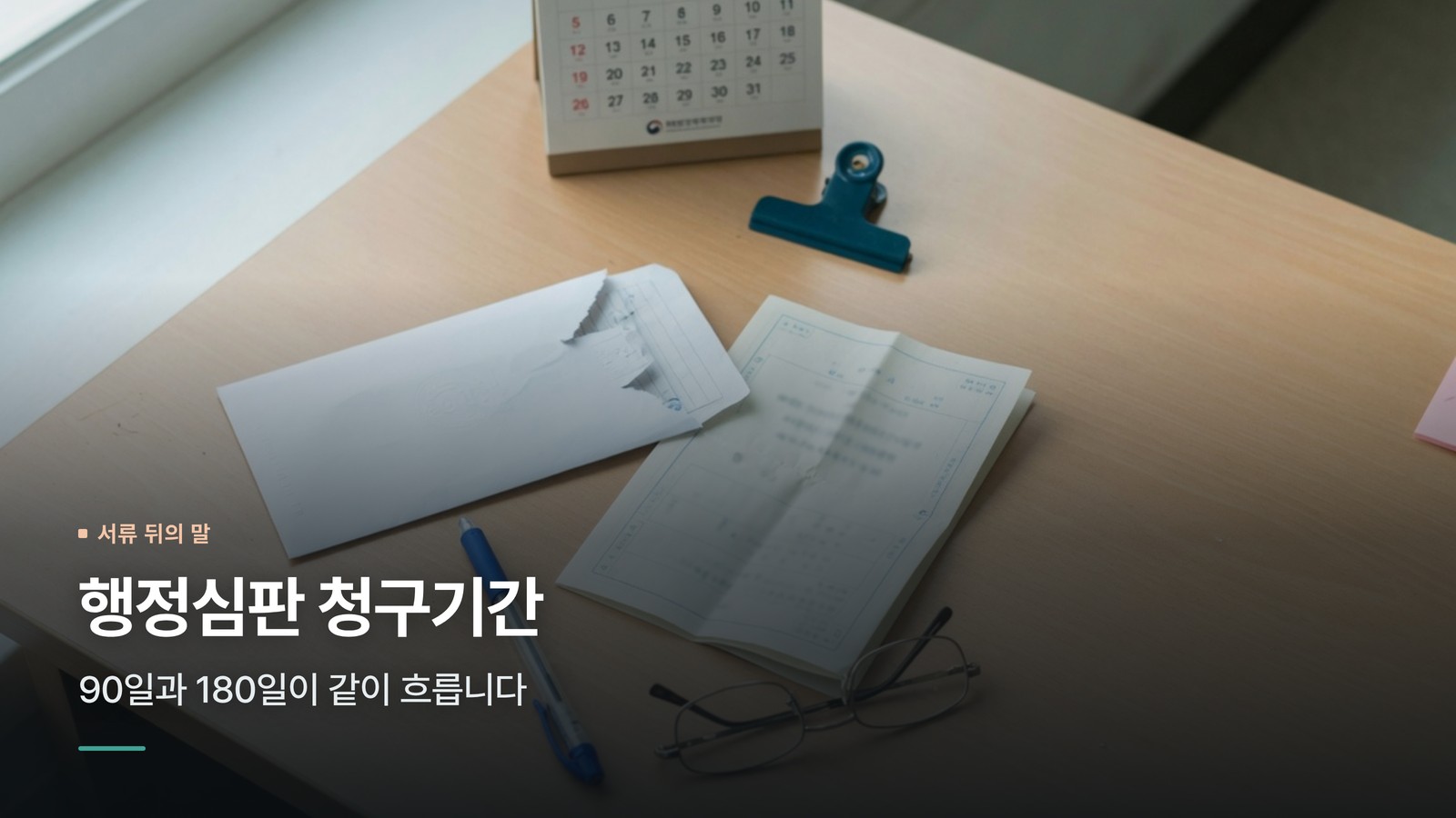 행정처분 통지서와 열린 봉투, 탁상 달력이 놓인 사무실 책상